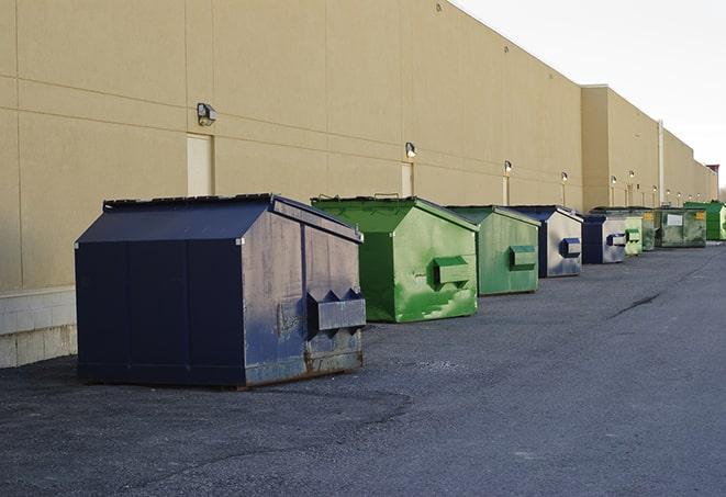 a construction worker empties a wheelbarrow of waste into the dumpster in Belleville, MI